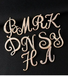 Detailed close-up of vintage gold-tone pearl alphabet brooches on black leather