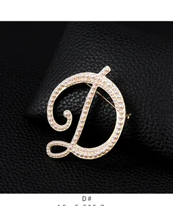 Detailed close-up of a vintage gold-toned letter D brooch encrusted with white pearls