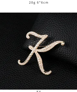 Elegant gold-tone letter K brooch adorned with white pearls on a black leather background
