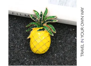 Detailed view of a vibrant yellow enamel pineapple brooch with green rhinestones.