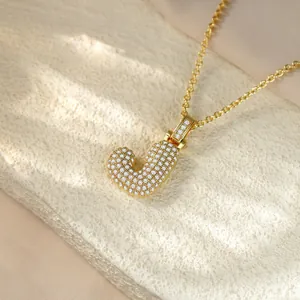 Macro detail view of a shiny iced out gold-plated letter J pendant hip-hop necklace