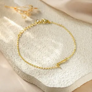 Close-up detail of gold titanium steel bracelet featuring a minimalist letter L charm