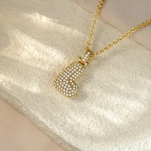 Close-up of iced out gold letter B pendant necklace with pavé set crystals