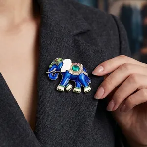 Vintage blauwe olifant broche met groen kristal op revers van pak