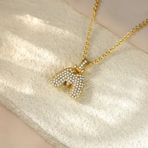 Detail macro shot of gold-plated pendant necklace featuring an iced-out letter M.