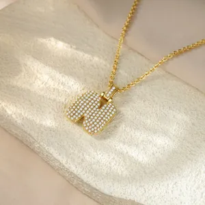 Close-up of iced-out gold letter N pendant necklace with sparkling pave crystals.