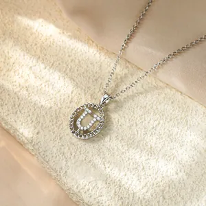 Primo piano del ciondolo a lettera U in argento con zirconi su una catenina sottile.