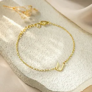 Close-up of a minimalist gold titanium steel bracelet with an initial U pendant.
