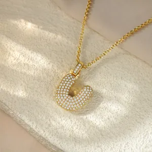 High-quality close-up of a gold iced-out bubble letter U pendant necklace with shiny crystals