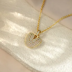 Detailed close-up of a gold-toned heart pendant necklace fully encrusted with clear stones.