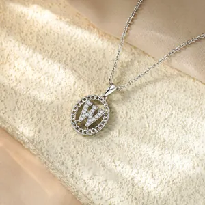 Dettaglio macro di una collana in argento con ciondolo a lettera W in zirconi cubici.