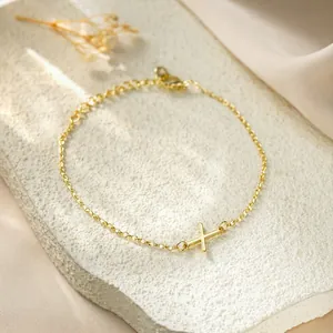 Close-up of gold titanium steel bracelet featuring a minimalist X letter charm
