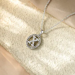 Dettaglio del ciondolo iniziale X in argento con zirconi micro-pave su fondo materico.