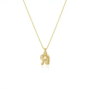 Detail view of an elegant golden letter R pendant necklace with intricate floral engravings