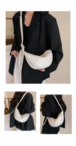 Detaillierte Ansichten einer weißen Halbmond-Schultertasche an einem Model in einem Blazer.