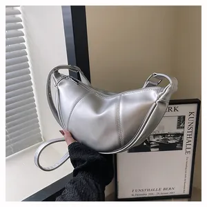Detailansicht einer silbernen, halbmondförmigen Tasche mit vertikalen Nähten