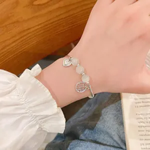 Vista detallada de una elegante pulsera de cuentas de cerámica macaron con dijes de corazón