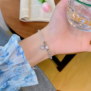 Vista detallada de una pulsera de cuentas macaron con un dije de estrella.
