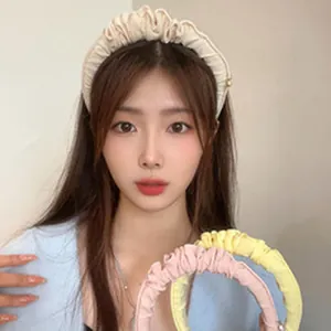 Close-up of Asian model wearing a beige pleated headband with more color options displayed