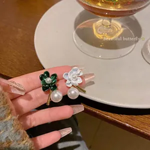 Detailed view of French-style floral pearl earrings with enamel petals and large pearl drop