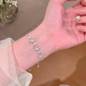 Close-up detail of a delicate silver-colored heart-shaped bracelet worn on the wrist