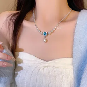 Collier élégant en perles avec pendentif bleu et perle goutte porté par un modèle