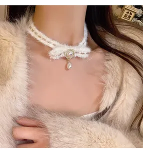 Gros plan d'un tour de cou en peluche avec pendentif perle élégant pour cet hiver.