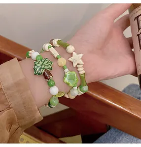 Primer plano de pulseras de cuentas de cerámica verde macarrón con dijes de árbol y estrella