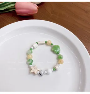 Primer plano de pulsera de cuentas de cerámica color macaron con dijes de flores.
