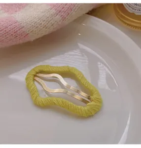 Detailed macro view of yellow yarn-wrapped wavy metal hair clip with soft winter texture