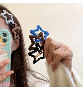 Detail view of colorful knitted star-shaped hair clips held in hand and styled in hair.