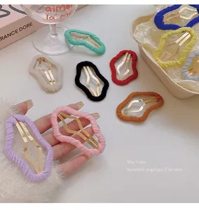 Detail of various colorful yarn-wrapped cloud hair clips shown on hand and props.