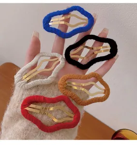 Close-up showing five colorful cloud-shaped fabric hair clips with gold metal base on hand