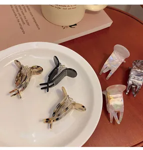 Variety of small resin hair claw clips displayed on a plate and wooden table.