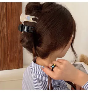 Detail view of small black and iridescent hair claw clips styling a bun on brown hair