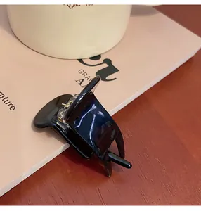 Detail view of small glossy black shark claw clip for elegant high ponytail hair styling
