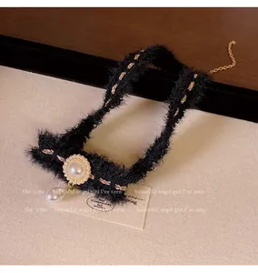 Gros plan d'un choker en peluche noire avec chaîne dorée et élégant pendentif en perle