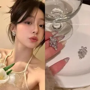 Detailed view of sparkling flower-shaped zircon stud earrings worn by a model