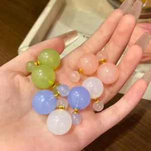 Elegant pastel color double-sided ball stud earrings shown in hand detail view
