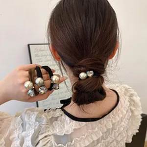Close-up detail of elegant pearl and crystal elastic hair ties shown in hand and hair