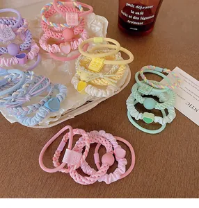 Pastel colored hair ties featuring heart charms and Hand Made tags on wooden table