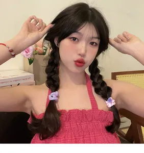 Sweet dopamine colored elastic hair ties worn on braided pigtails by a model in a lifestyle setting