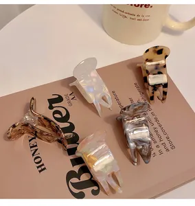 Detail view of colorful small acetate hair claw clips arranged on a vintage style book