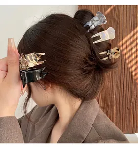 Detail of small acetate hair claw clips styled in a high ponytail bun for women