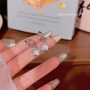 Close-up of silver star hoop earrings with shimmering opalescent center charms.
