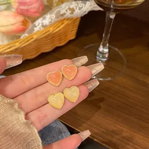 Close-up detail of charming heart-shaped stud earrings in orange and cream colors
