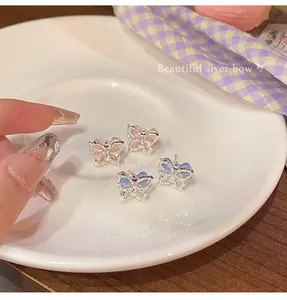 Detailed view of pink and blue butterfly stud earrings on a white ceramic plate