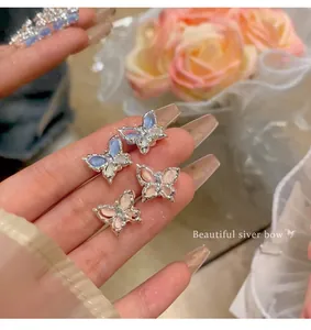Close-up detail of fairy-style pink and blue butterfly stud earrings with silver finish