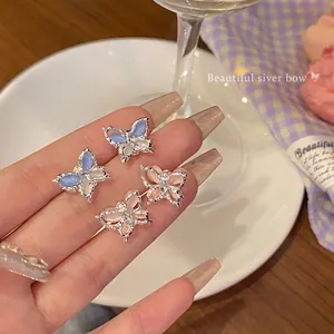 Elegant pink and blue butterfly stud earrings with silver finish in a lifestyle setting