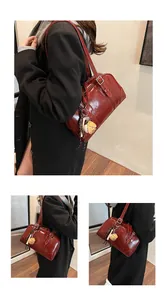 Stylish large burgundy glossy shoulder bag styled with a dark coat in an indoor setting